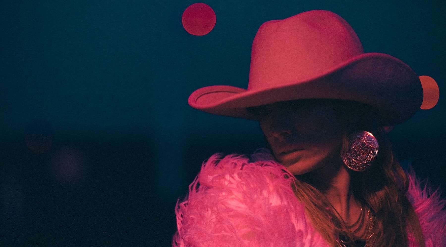 a woman in a pink hat and coat with the night sky in the background
